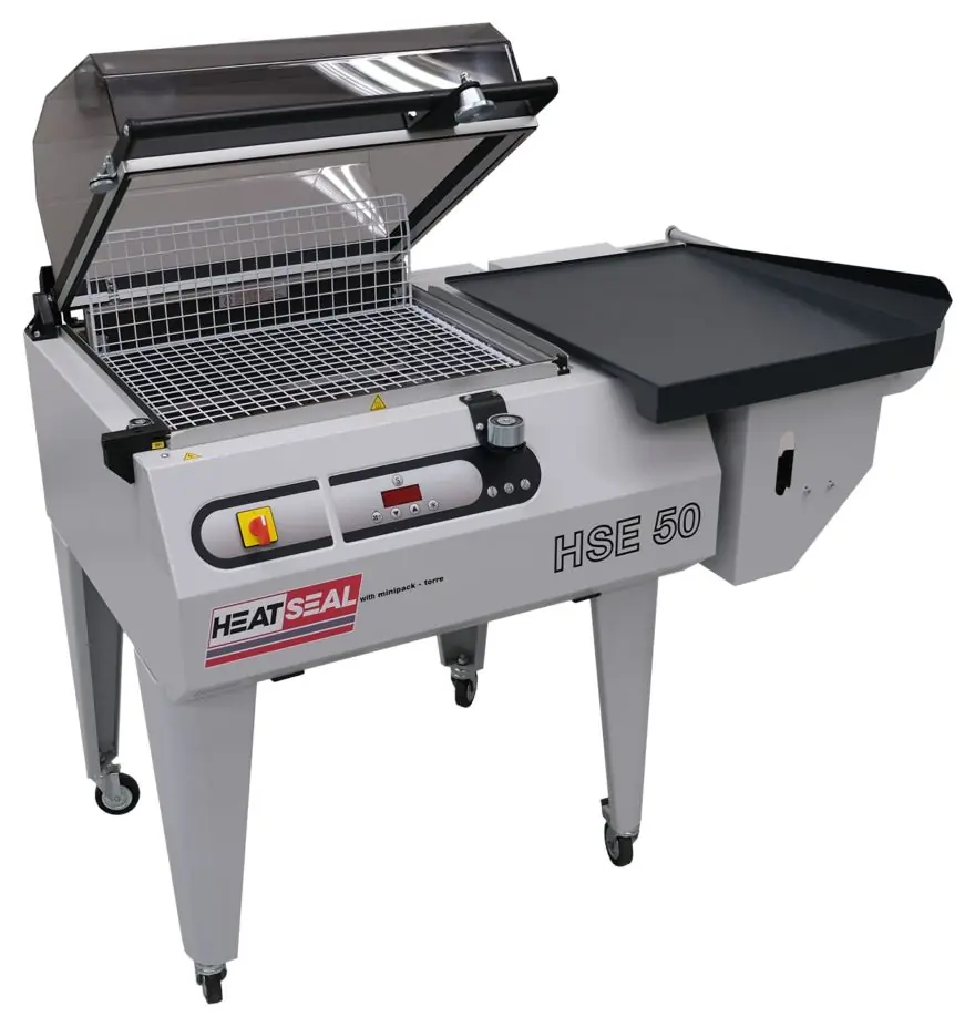 A Heat Seal HSE 50 with its clear hood raised over the sealing area and an outfeed table.