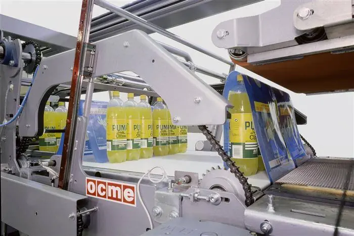 An industrial shrink bundler wrapping groups of plastic soft drink bottles in film.