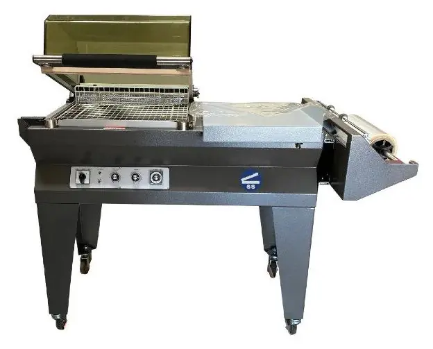 A compact L-bar sealer with a hinged shrink hood raised over a wire product tray.