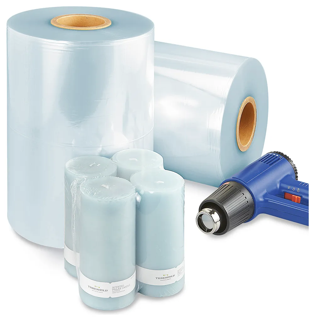 Two rolls of pale blue PVC shrink film, four pillar candles shrink wrapped together in clear film, and a blue heat gun.